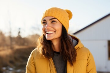 Portrait of a happy woman in her 40s dressed in a warm ski hat against a soft yellow background. AI Generation - obrazy, fototapety, plakaty