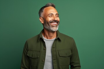 Fototapeta premium Portrait of a cheerful man in his 40s sporting a rugged denim jacket against a soft green background. AI Generation