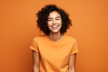 Portrait of a grinning woman in her 20s dressed in a casual t-shirt against a soft orange background. AI Generation