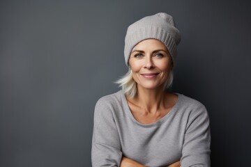 Portrait of a cheerful woman in her 40s sporting a trendy beanie against a soft gray background. AI Generation