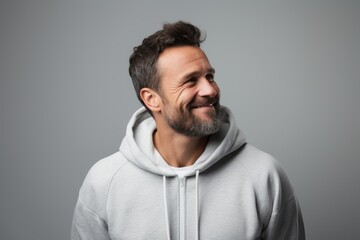 Fototapeta premium Portrait of a blissful man in his 40s sporting a comfortable hoodie against a soft gray background. AI Generation