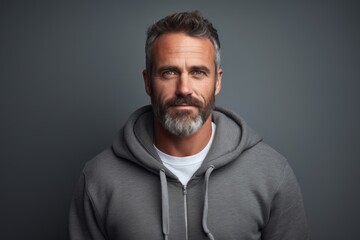 Obraz premium Portrait of a blissful man in his 40s sporting a comfortable hoodie against a soft gray background. AI Generation