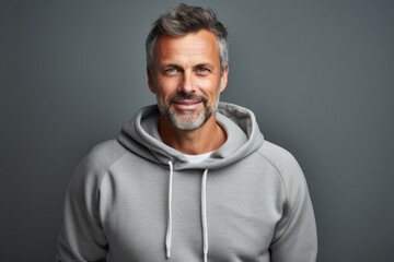 Fototapeta premium Portrait of a blissful man in his 40s sporting a comfortable hoodie against a soft gray background. AI Generation