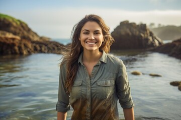 Portrait of a grinning woman in her 30s sporting a vented fishing shirt against a peaceful tide pool background. AI Generation - obrazy, fototapety, plakaty