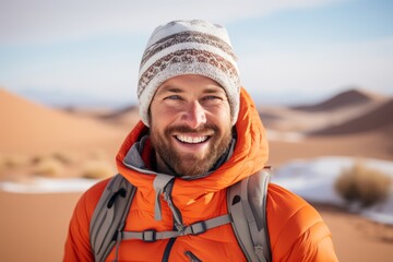 Portrait of a cheerful man in his 30s dressed in a warm ski hat against a serene dune landscape background. AI Generation