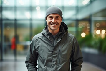 Fototapeta na wymiar Portrait of a smiling man in his 40s wearing a lightweight packable anorak against a sophisticated corporate office background. AI Generation