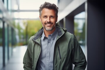 Portrait of a smiling man in his 40s wearing a lightweight packable anorak against a sophisticated corporate office background. AI Generation - obrazy, fototapety, plakaty