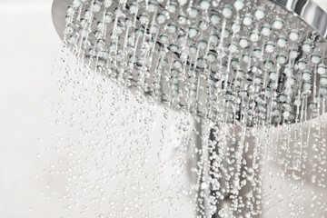 Clean water drops pours from the shower head in the light bathroom. Detailed water and shower...
