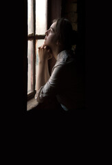 Young girl at the old wooden window