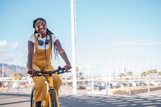 Young woman riding a yellow bicycle and smiling on a ride through the city. Concept: lifestyle, outdoors.