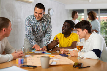 Fototapeta premium Group of active men play board games during a friendly meeting