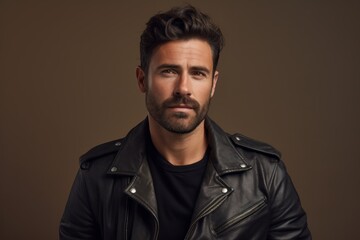 Obraz premium Portrait of a satisfied man in his 30s sporting a classic leather jacket against a pastel or soft colors background. AI Generation