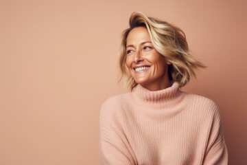 Portrait of a joyful woman in her 40s dressed in a warm wool sweater against a pastel or soft...