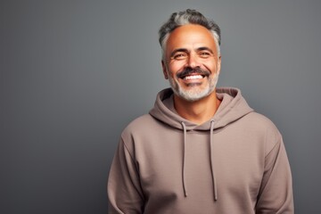 Portrait of a smiling man in his 50s sporting a comfortable hoodie against a minimalist or empty room background. AI Generation