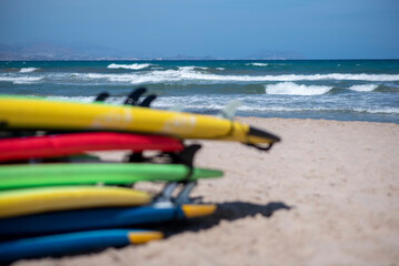 Set of different color surf boards in a sandy. Surf boards for rent on sandy beach. Soft toned...