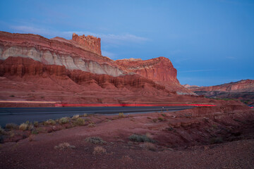 Closeup image of a rock formation in Utah with streaks of light from cars traveling over a road