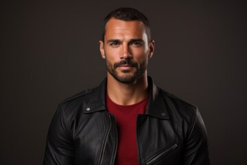 Fototapeta premium Portrait of a satisfied man in his 30s sporting a classic leather jacket against a solid color backdrop. AI Generation