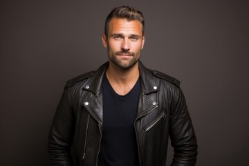 Obraz premium Portrait of a satisfied man in his 30s sporting a classic leather jacket against a solid color backdrop. AI Generation