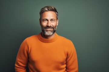 Fototapeta premium Portrait of a happy man in his 40s dressed in a warm wool sweater against a solid color backdrop. AI Generation