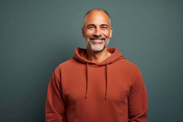 Portrait of a grinning man in his 50s dressed in a comfy fleece pullover against a solid color...