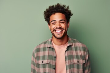 Fototapeta premium Portrait of a happy man in his 20s dressed in a relaxed flannel shirt against a solid color backdrop. AI Generation