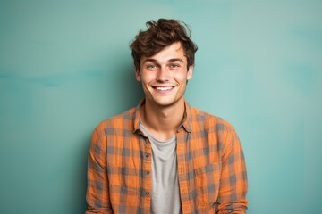 Obraz premium Portrait of a happy man in his 20s dressed in a relaxed flannel shirt against a solid color backdrop. AI Generation