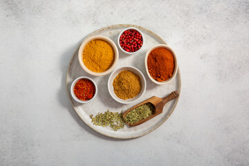 Obraz na płótnie Canvas Assorted colorful spices in small bowls on tray on gray background. Food background. Top view, copy space.