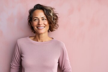 Obraz premium Portrait of a smiling woman in her 40s showing off a thermal merino wool top against a solid pastel color wall. AI Generation