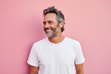 Portrait of a happy man in his 40s sporting a vintage band t-shirt against a solid pastel color...