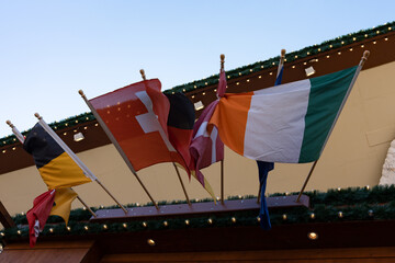 Several flags of different countries intertwine together in the wind. Flag of Ireland, flag of...