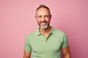 Portrait of a grinning man in his 40s wearing a sporty polo shirt against a solid pastel color...