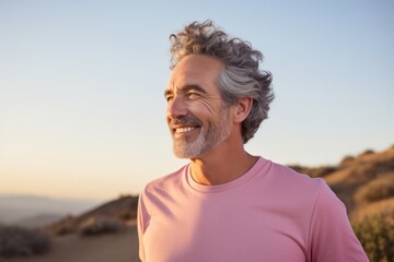 Portrait of a smiling man in his 50s sporting a breathable mesh jersey against a solid pastel color...