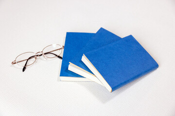 青いブックカバーの３冊の本とメガネ