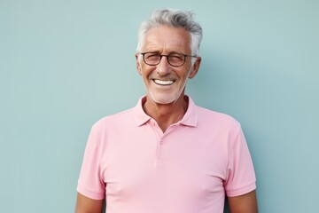 Portrait of a joyful man in his 80s donning a classy polo shirt against a solid pastel color wall....