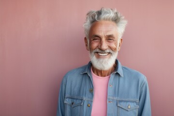 Portrait of a cheerful man in his 70s sporting a versatile denim shirt against a solid pastel color...