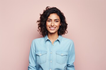 Portrait of a blissful woman in her 20s sporting a versatile denim shirt against a solid pastel...