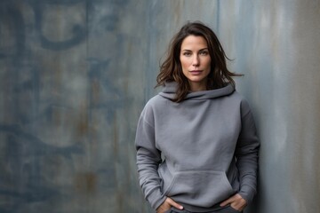 Naklejka premium Portrait of a glad woman in her 30s wearing a thermal fleece pullover against a bare concrete or plaster wall. AI Generation