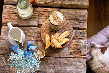 still life with a cappuccino and biscotti on a wooden table.
