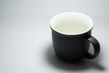 An empty dark grey real mug isolated on white background with clear and natural texture for background. Artistic shading of porcelain or ceramic mug.