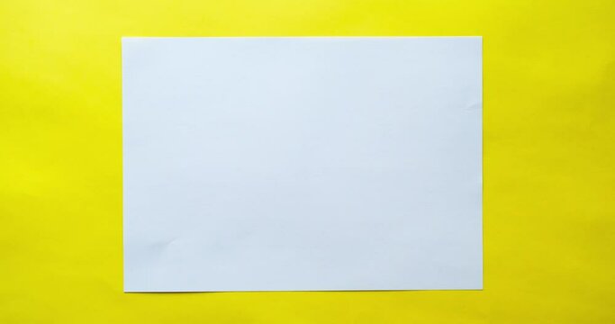 The blank white paper sheet is straightening. 4K stop motion animation on yellow background