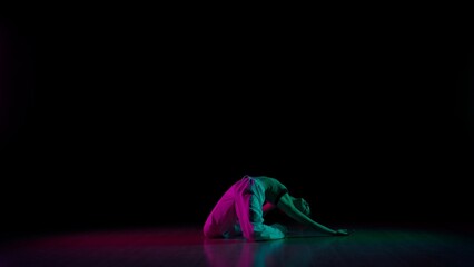 Attractive girl in casual posing on the floor, showing contemporary choreography, black background...