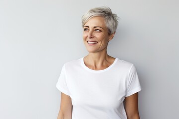 Portrait of a tender woman in her 50s dressed in a casual t-shirt against a plain white digital canvas. AI Generation