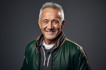 Obraz premium Portrait of a smiling man in his 60s sporting a stylish varsity jacket against a plain white digital canvas. AI Generation