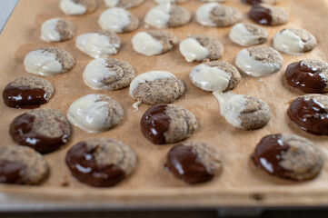 Fresh glazed christmas cookies with poppy seeds and white and dark chocolate glaze on a baking sheet