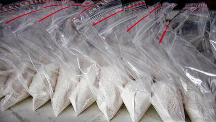 A large number of transparent sachets filled with white powder. White powder packaged in small...