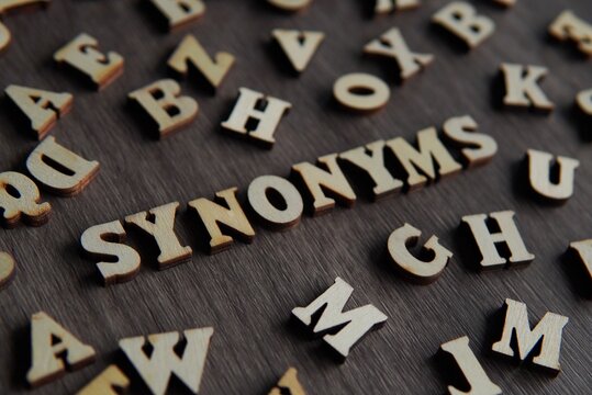 Closeup image of text SYNONYMS surrounded by scattered alphabet.