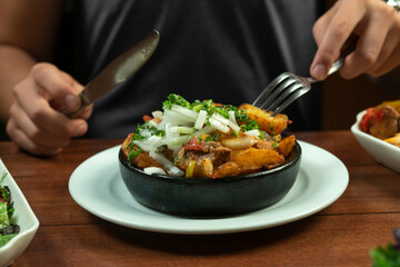 Man eating Beef stew with potatoes, carrots and herbs on black background with copy