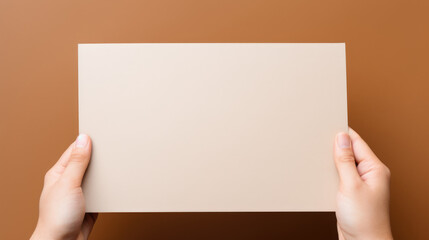 Obraz premium Hand hold a discount card, business card, mockup of a blank white sheet of paper on a tan background with copy space. Template for design. layout. copy space for text.