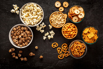 Set of many salty snacks in bowls - pretzels nuts chips top view