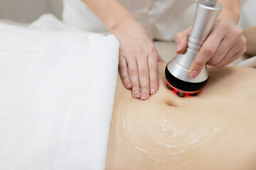 RF body cavitation lifting procedure in a beauty salon. Ultrasound therapy to reduce fat and elasticity of the skin. Cosmetic ultrasonic anti-cellulite massage close-up - obrazy, fototapety, plakaty